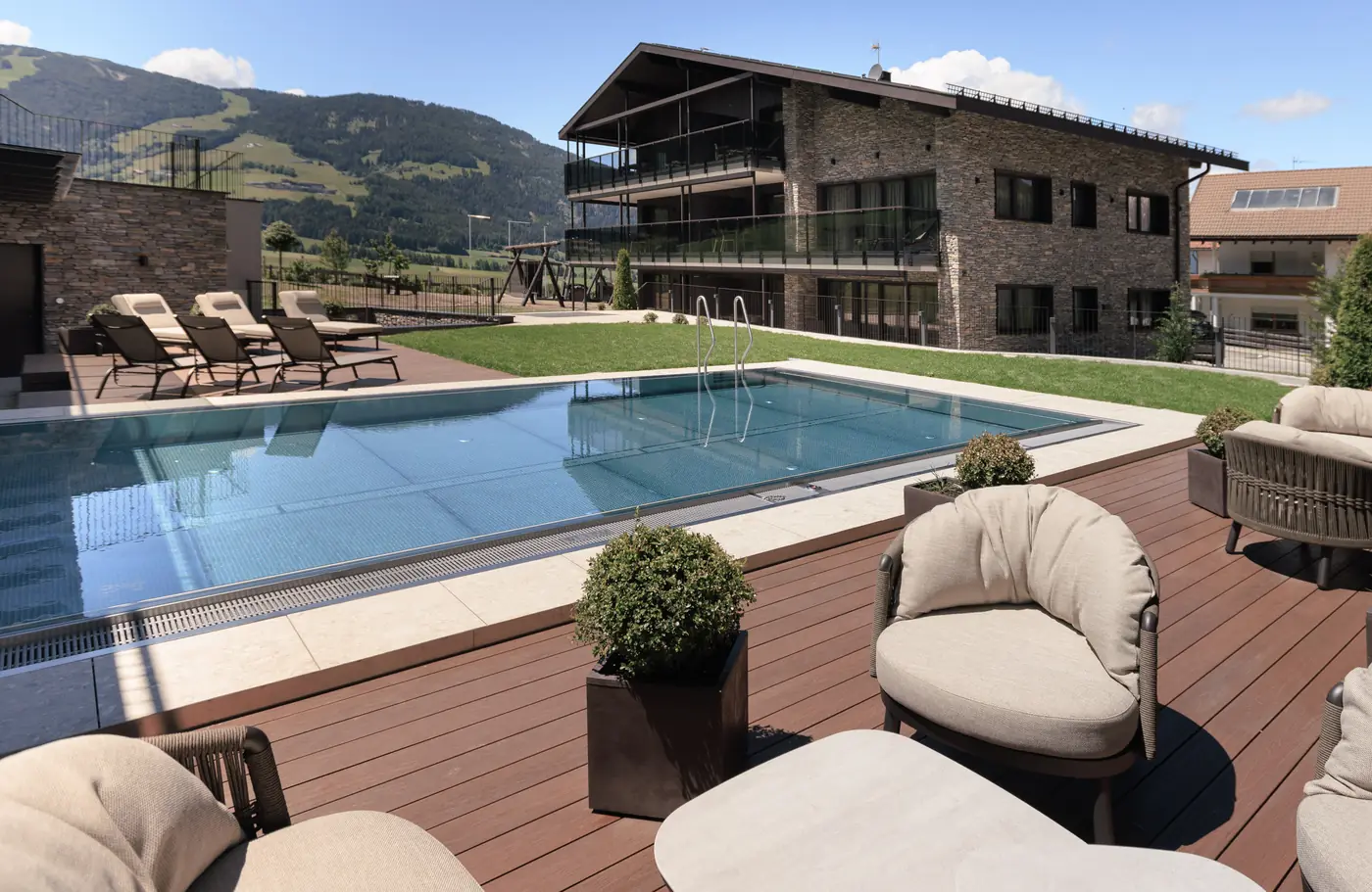 Das Suitehouse mit Außenpool und Lounge-Sesseln vor den Bergen
