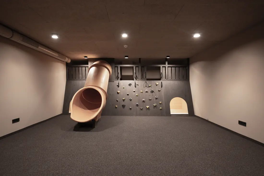 Kinderspielraum mit Rutsche aus der Wand und Kletterwand