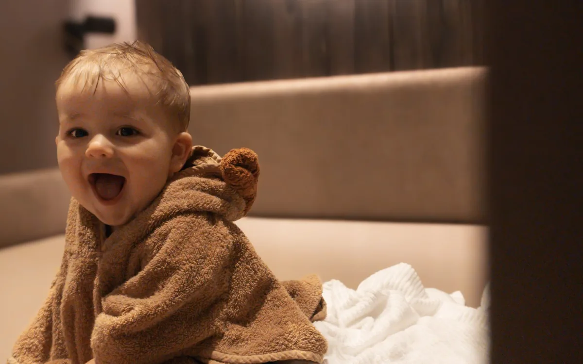 Baby im Bärchen-Bademantel lacht im Ruheraum des Family Spa