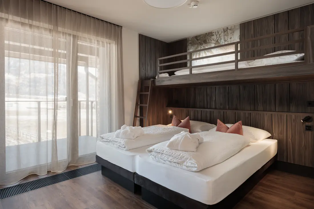 Schlafzimmer mit Doppelbett, Stockbett und bodentiefen Fenstern